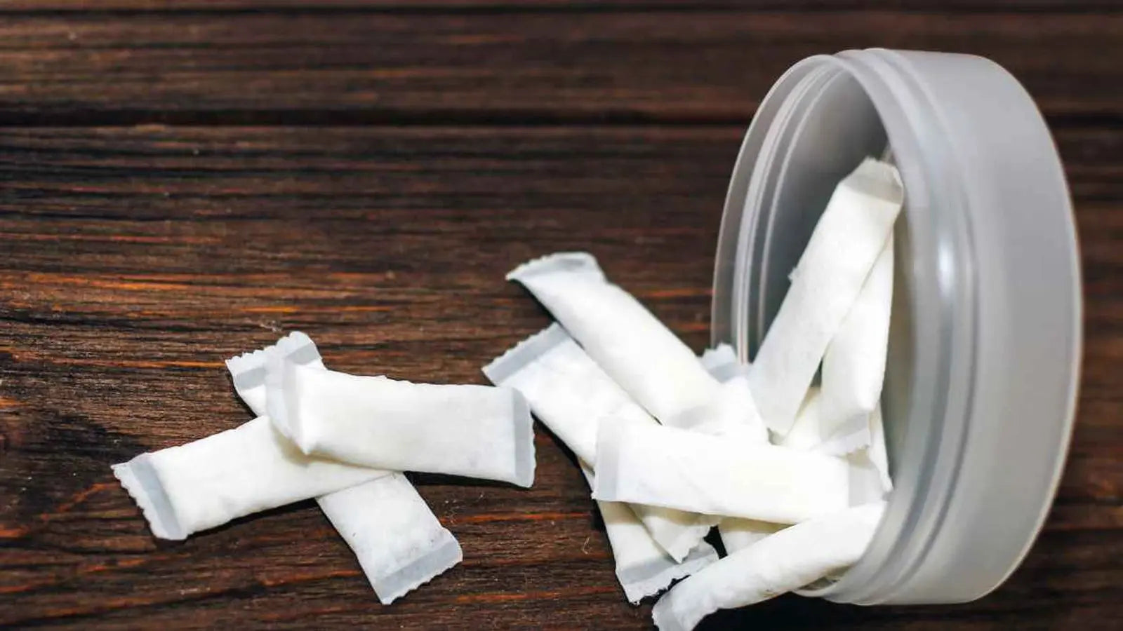 Nikotinové sáčky vysypané z krabičky na dřevěném podkladu