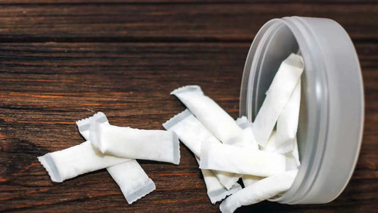 Nikotinové sáčky vysypané z krabičky na dřevěném podkladu