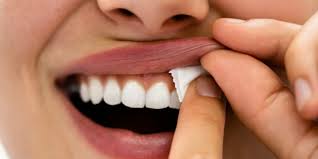 Ženská tvář s rukou držící nikotinový sáček, který si vkládá do úst